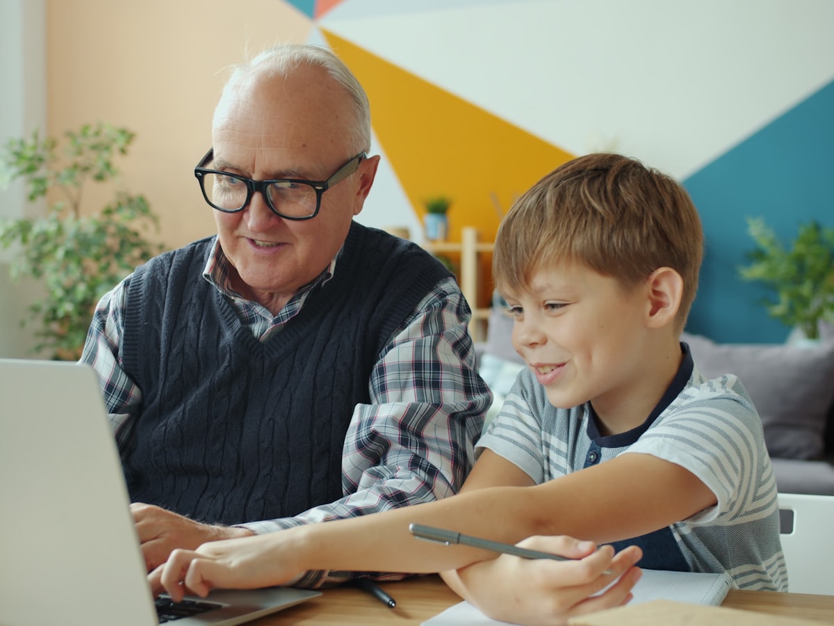 An older man and a child at a laptop together.